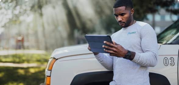 A business owner looks at his tablet on the job site in front of his work truck.