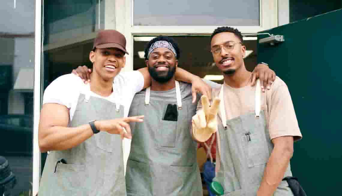 Three people in chef's hats smile while posing for a picture.