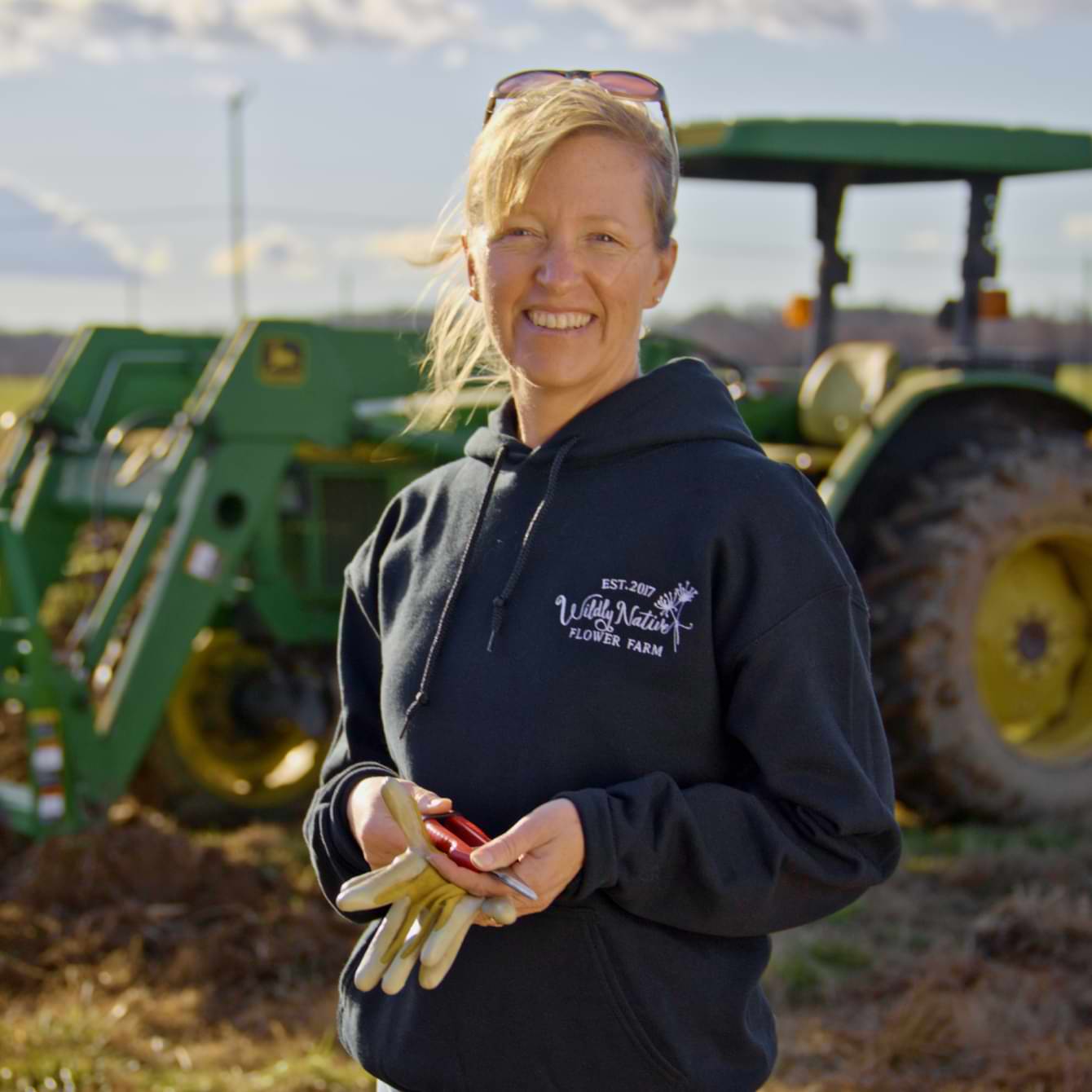 QuickBooks customer Liza Goetz, owner of a flower farm, is standing outside in front of a tractor