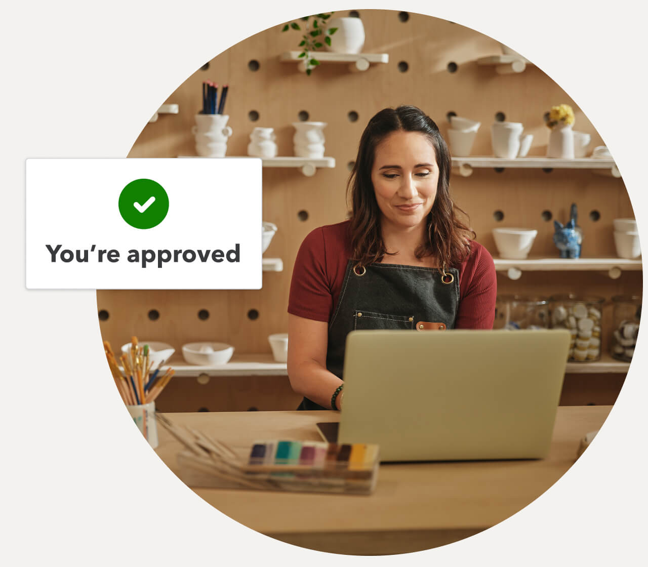 Person working on a laptop in a pottery studio with a snapshot of approval.