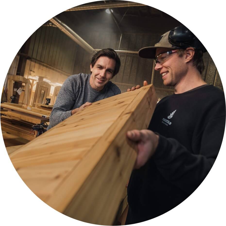 Two men examining a piece of a sauna inside a manufacturing facility.