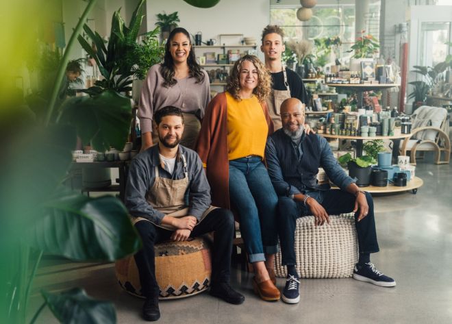 A group of people sitting around a table with vases.