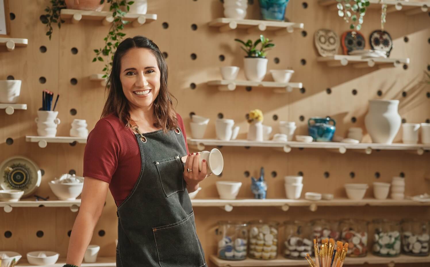 A person smiles as she holds a coffee cup.