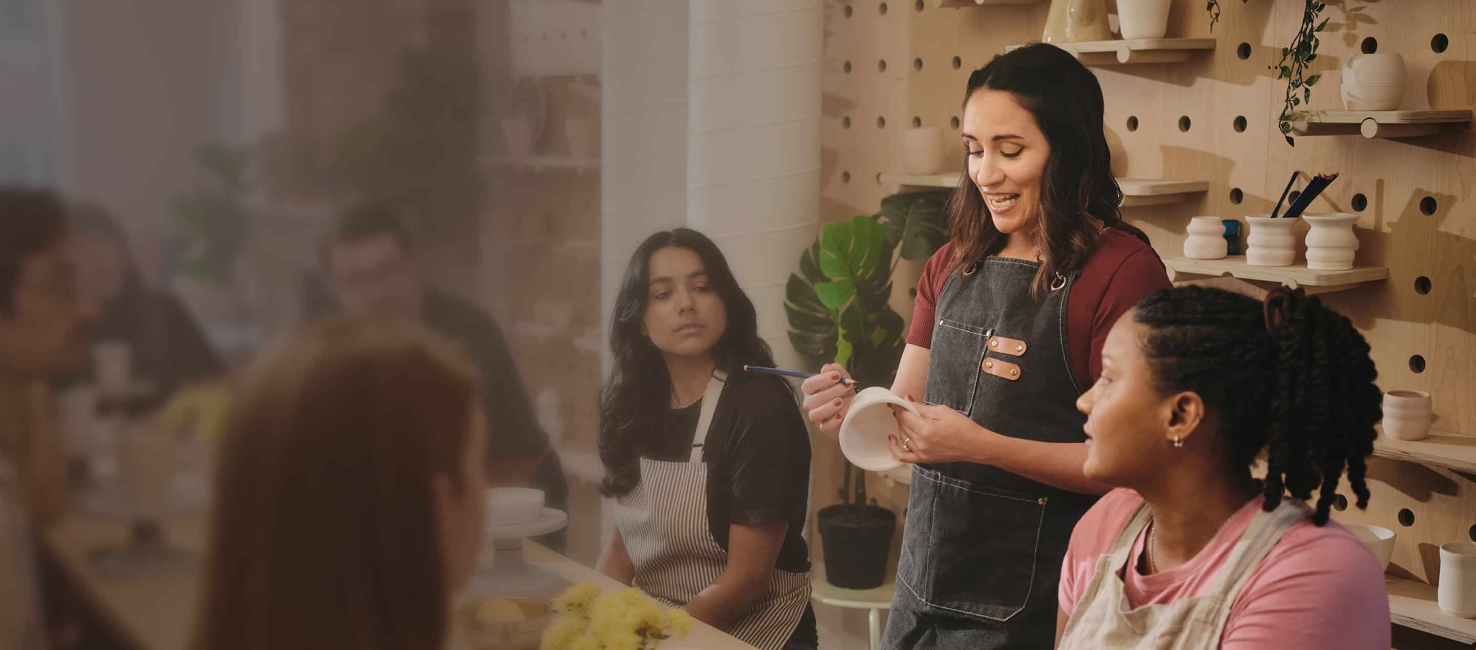 Studio owner shows students how to make a clay pot