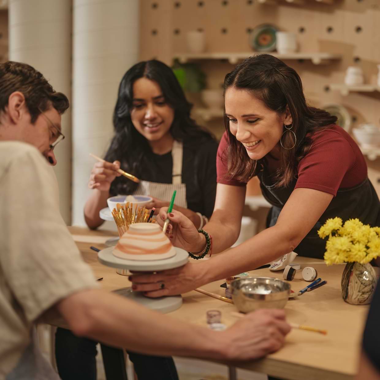 Studio owner helps student paint a clay bowl