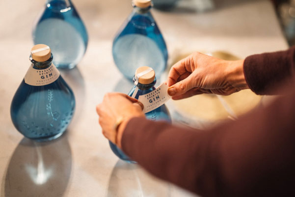 Woman applying label to bottle of gin