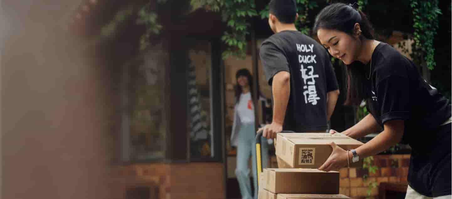 Two business owners are loading boxes of their chili onto a dolly.