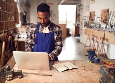 Owner of a woodwork studio using laptop to run payroll.