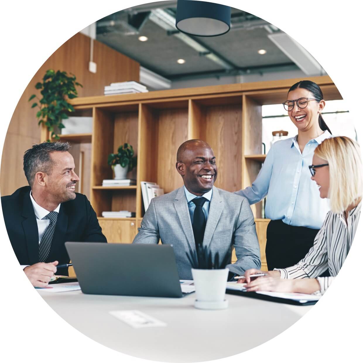 A group of four employees at a law firm gathered at a conference table and smiling and laughing with each other.