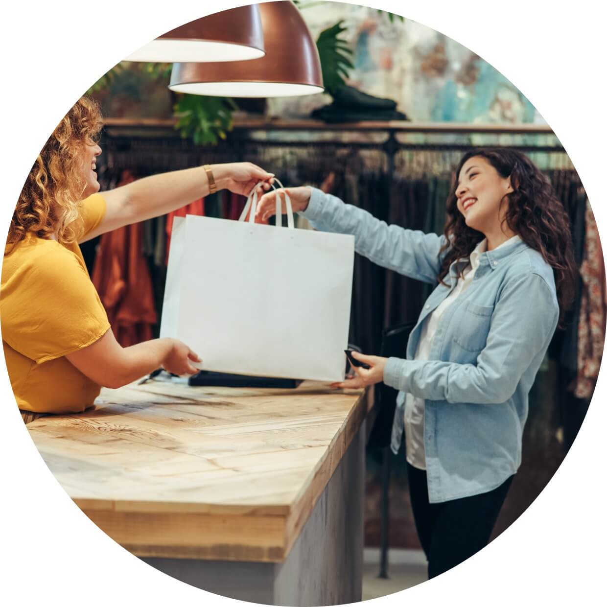 A store owner completing a sale and handing over a bag to a customer at the checkout counter.