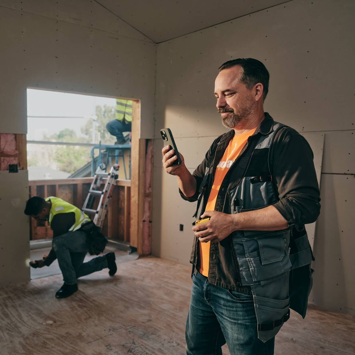 Contractor inside a house, one is looking at his phone.