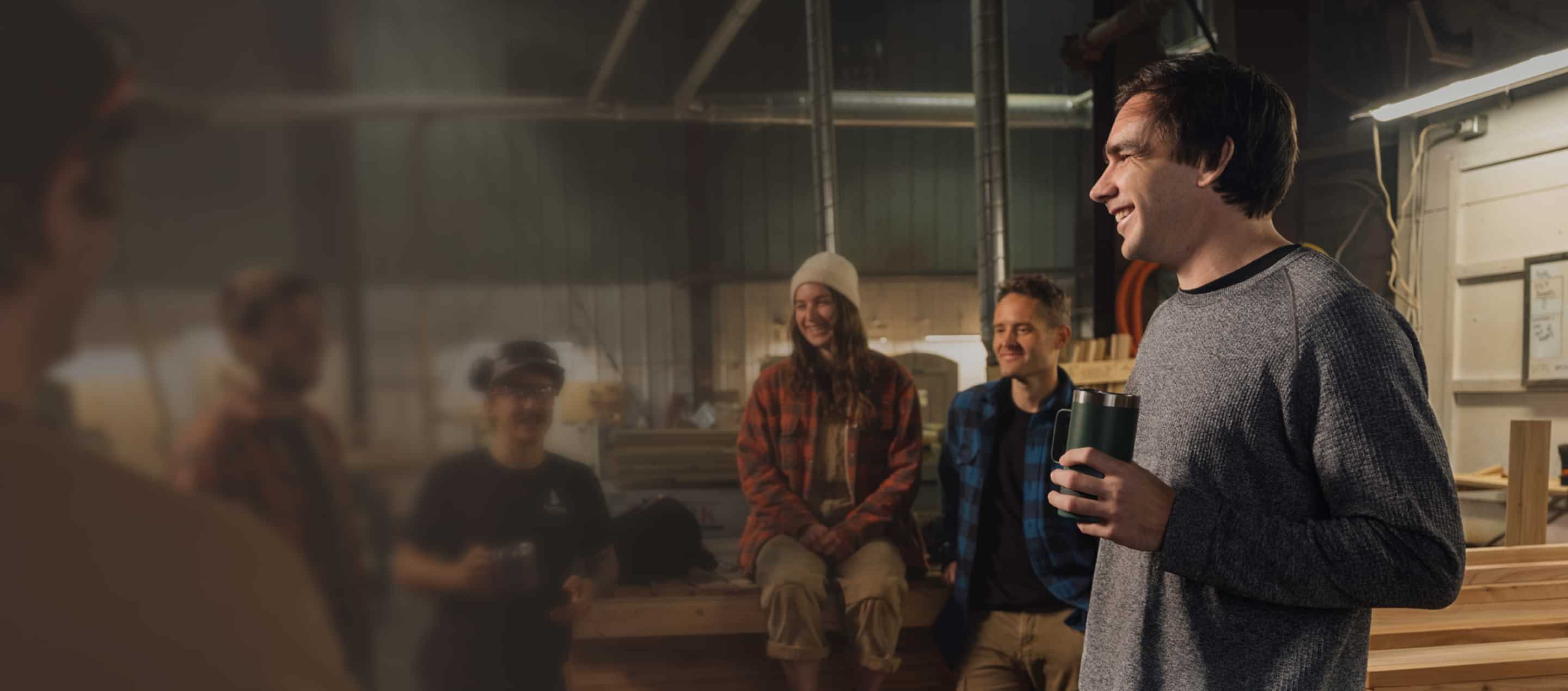 Business owner and employees taking a coffee break in a manufacturing warehouse.