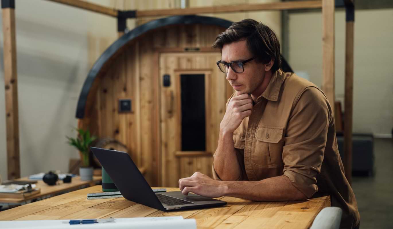 Business owner using a laptop to work while in the manufacturing warehouse.