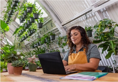 Woman using computer in plant store