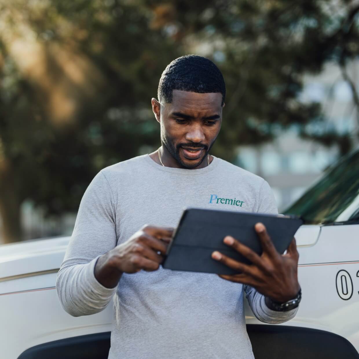 -Landscaper conducting business on a tablet while on-site at a field.