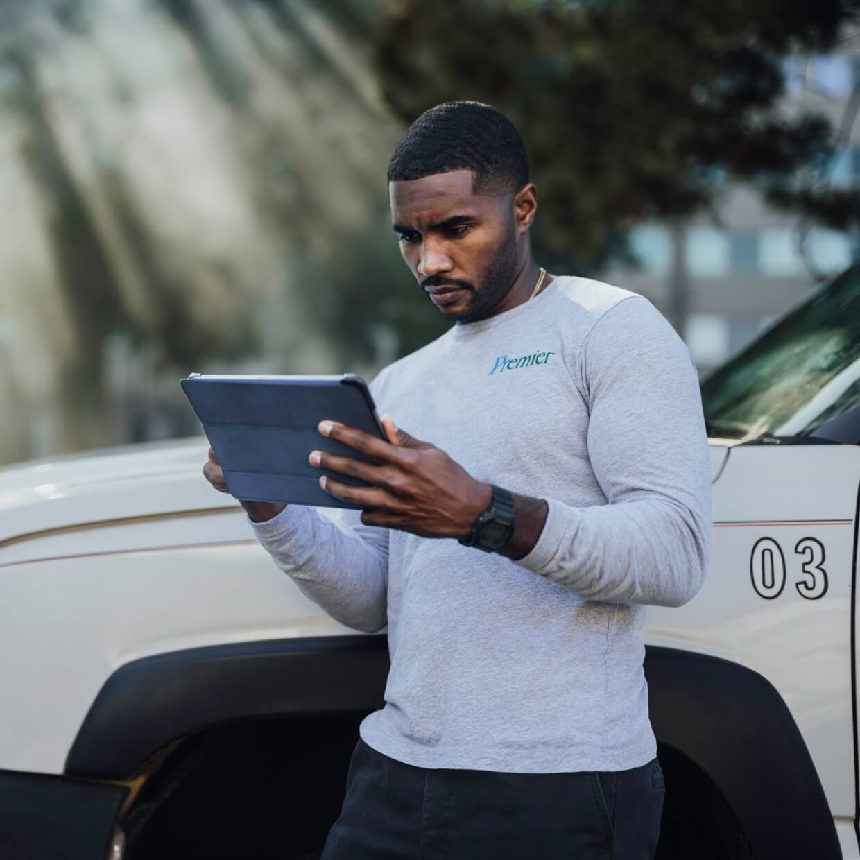 Landscaper concentrating on conducting business using a tablet while on-site at a field.