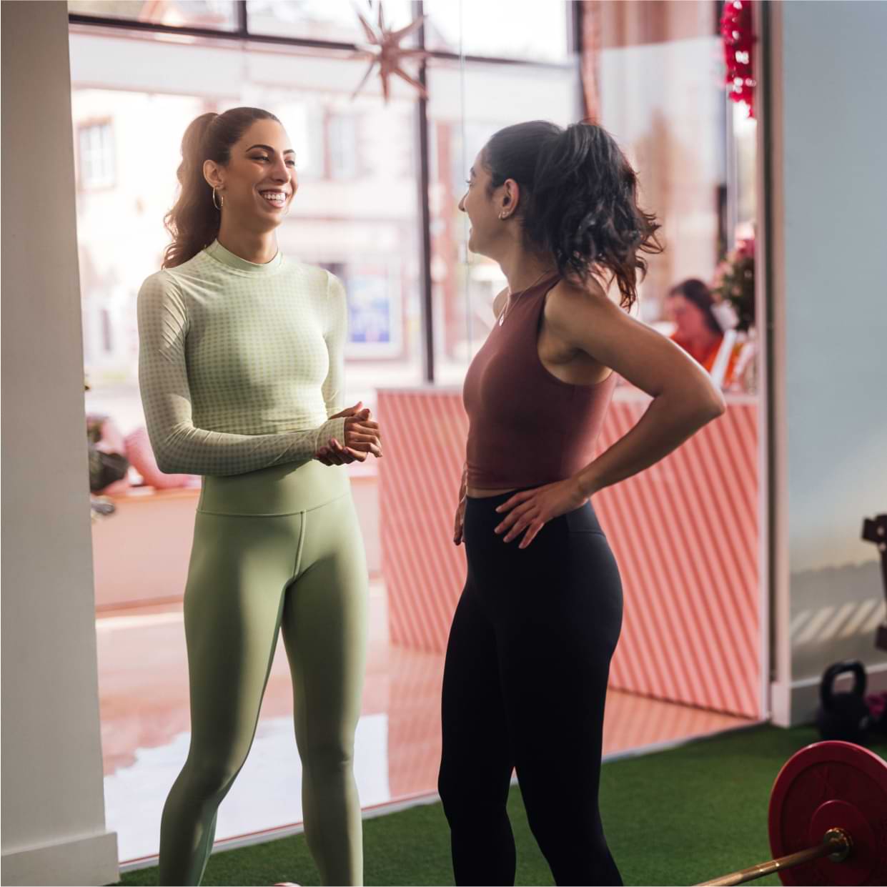 Personal trainer smiling and laughing with a client in a gym studio.