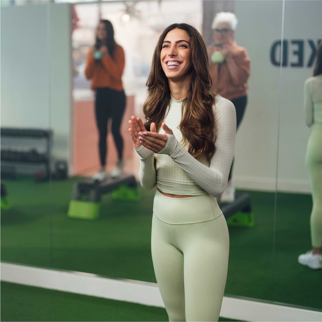 Gym instructor encouraging a group of clients during a class at a gym studio.