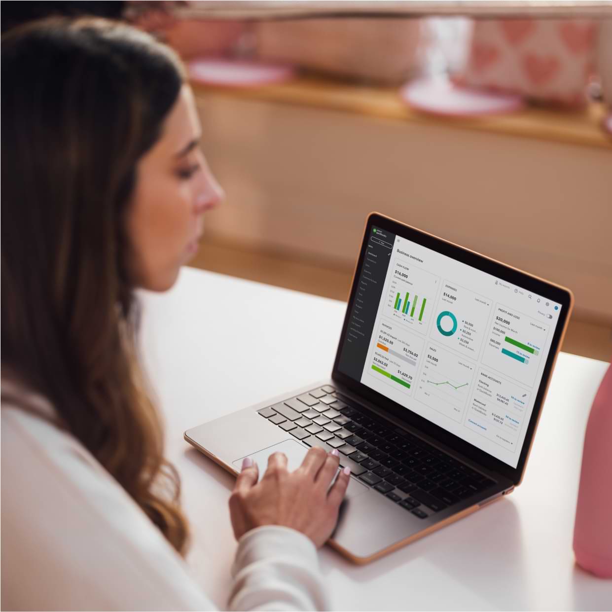 Gym owner sitting at a desk in the studio reviewing her business finances in QuickBooks. 