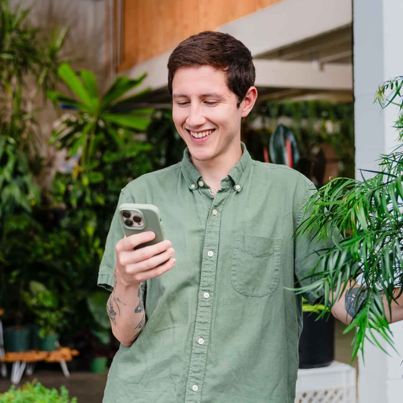 Plant store owner looking at his phone smiling
