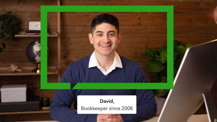 A QuickBooks bookkeeper named David is sitting at a desk and smiling. 