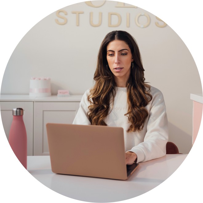 Business owner of Sculpt Studios sitting at a desk looking at a laptop