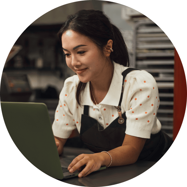 Small business owner reviews cash flow in QuickBooks Online while working on a laptop in a bakery.