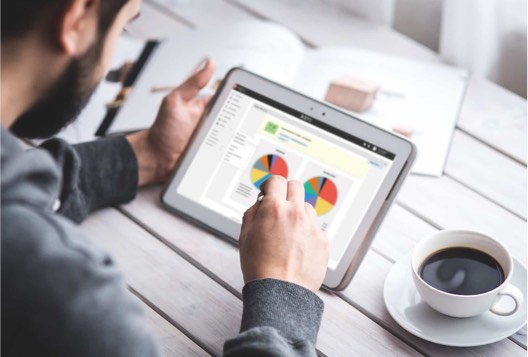 Business owner looking at QuickBooks Time labour report on a tablet device.