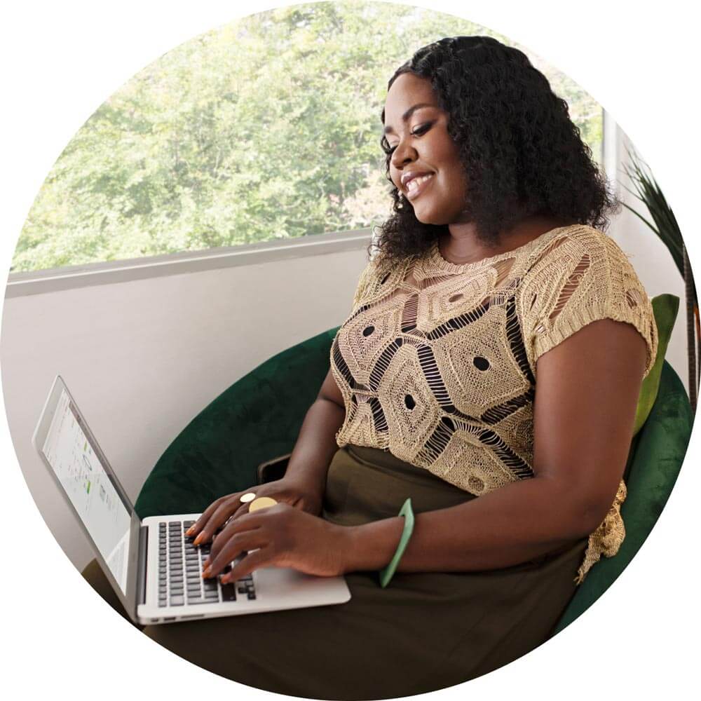 A person sitting on a chair with a laptop.