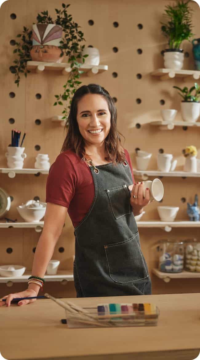 ledger.jpg A person smiles as she holds a cup of coffee.