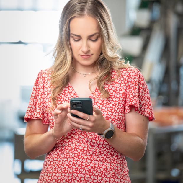 Une propriétaire d'entreprise consulte l'application QuickBooks sur son téléphone portable