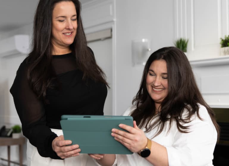 Une femme tend une tablette informatique à son collègue assis.