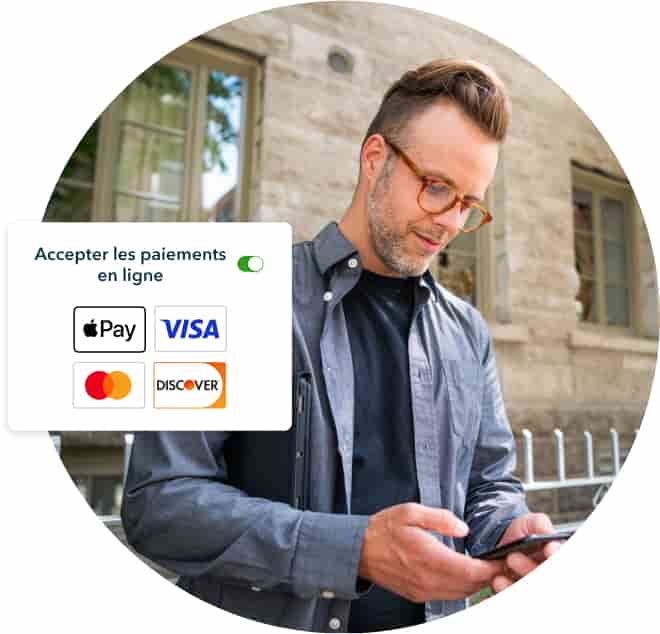 Propriétaire d’une petite entreprise regardant son téléphone cellulaire devant un bâtiment. Une capture d'écran indique « Accepter les paiements en ligne » avec les logos Apple Pay, Visa, Mastercard et Discover.